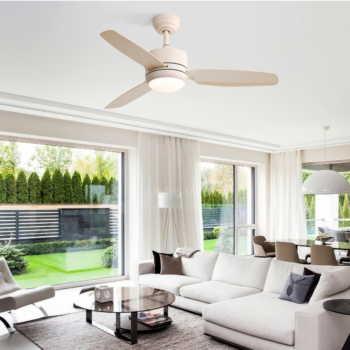Deckenventilator in einem Raum installiert. Weiß, mit hellbraunen Flügeln. Fenster und ein weißes Sofa sind ebenfalls sichtbar.