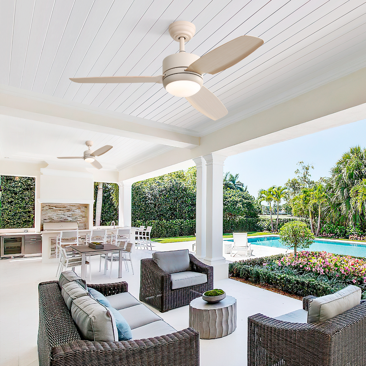 Terrasse im Freien mit Deckenventilatoren, Sitzgelegenheiten und Blick auf Pool und Grün.