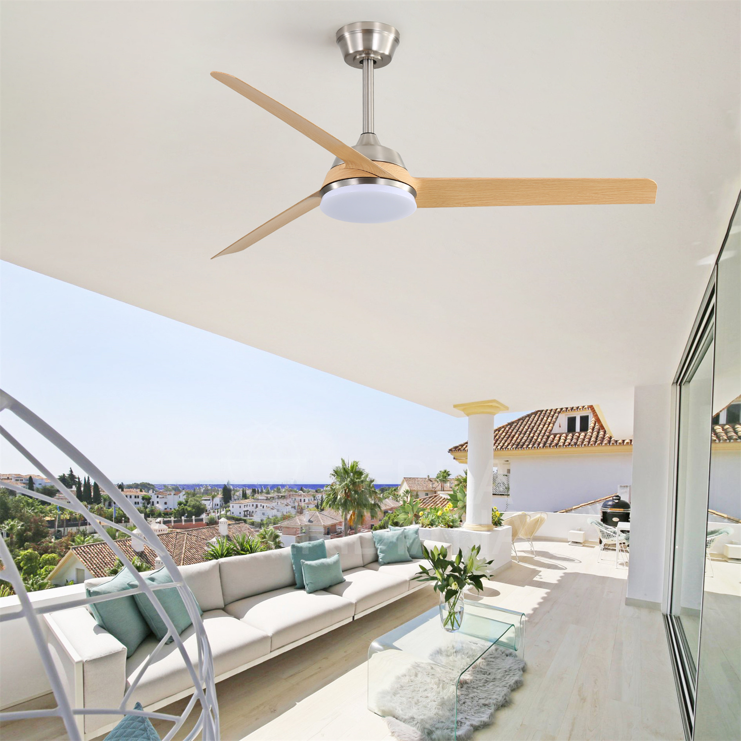 Deckenventilator mit Holzflügeln auf einem Balkon mit Blick auf eine sonnige Landschaft mit weißem Sofa.