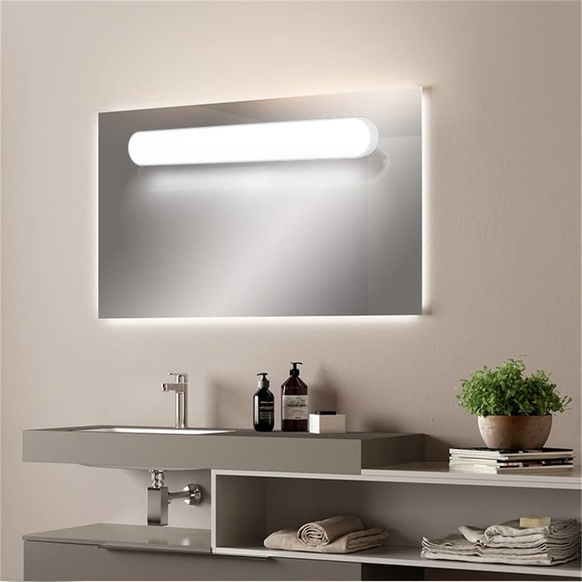 Badezimmerspiegel mit integriertem Licht über einem Waschbecken. Es gibt eine kleine Pflanze und Toilettenartikel.
