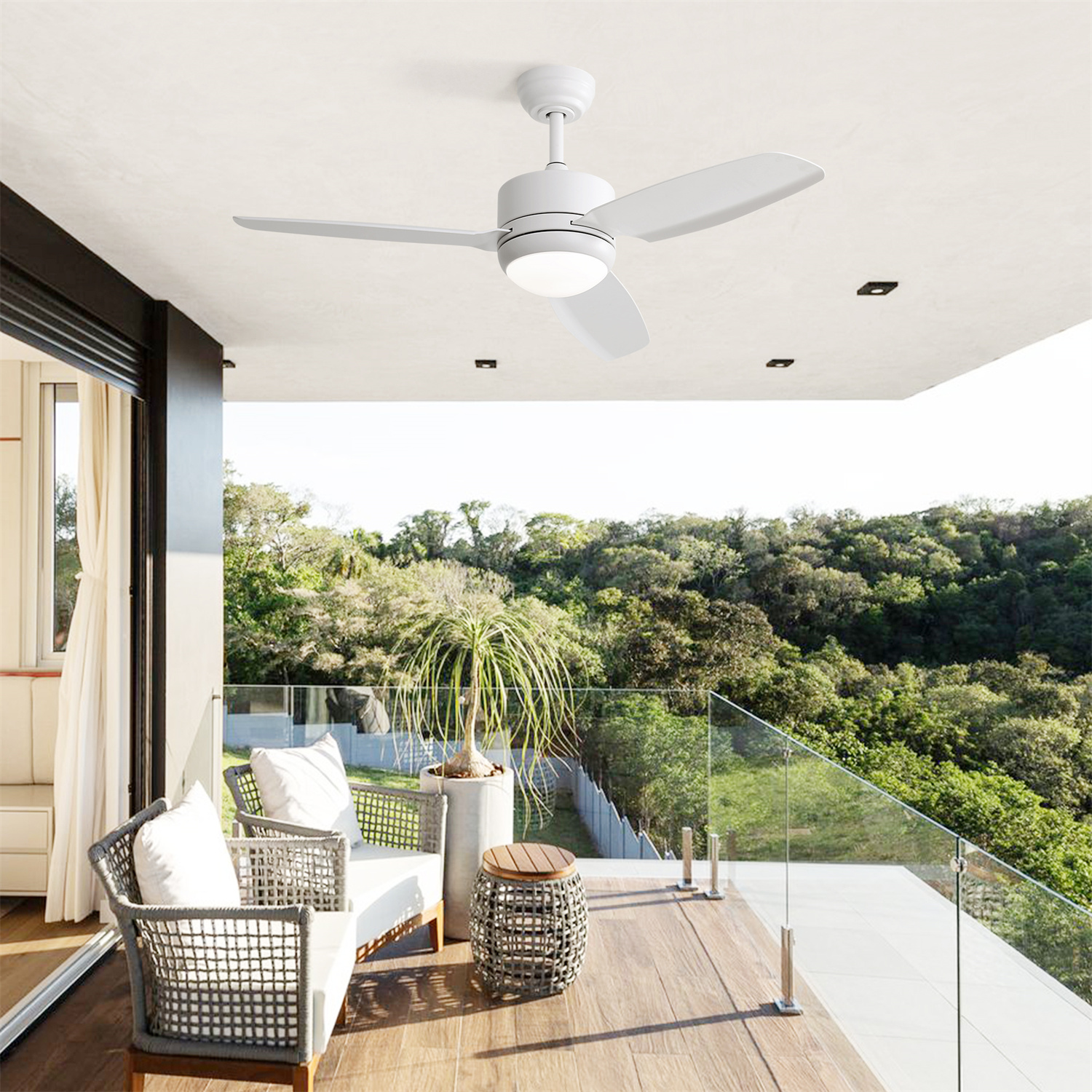 Terrasse im Freien mit Deckenventilator, weißen Stühlen und Blick auf Bäume. Es ist ein heller, sonniger Tag.