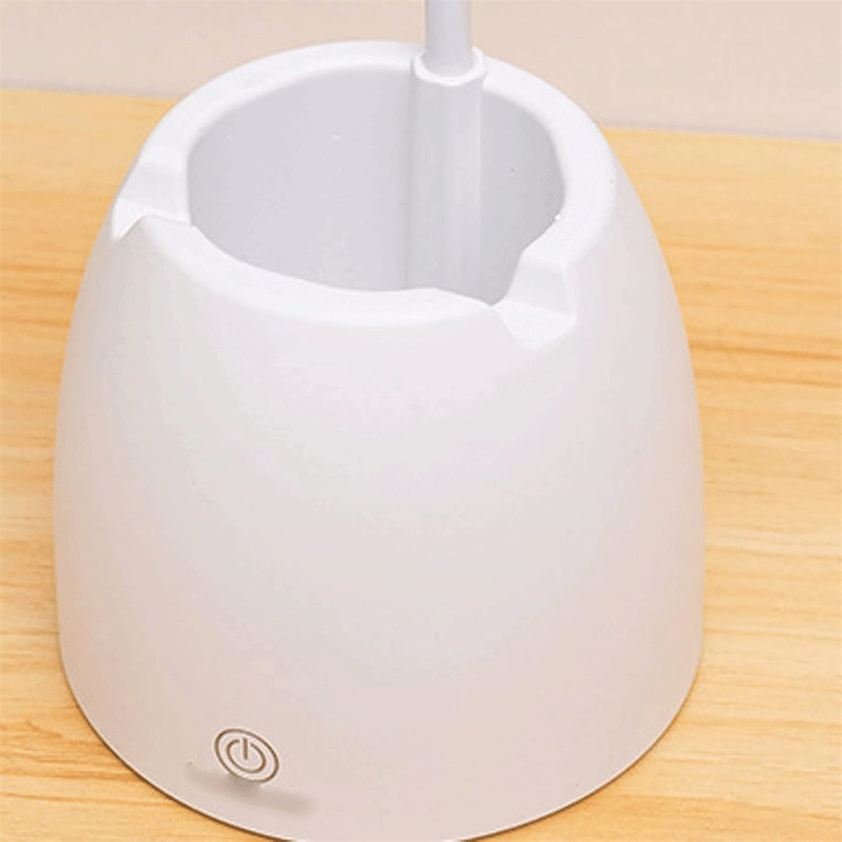 Ein weißer Aschenbecher mit einem Stromsymbol auf dem Boden, auf einer Holzoberfläche platziert.