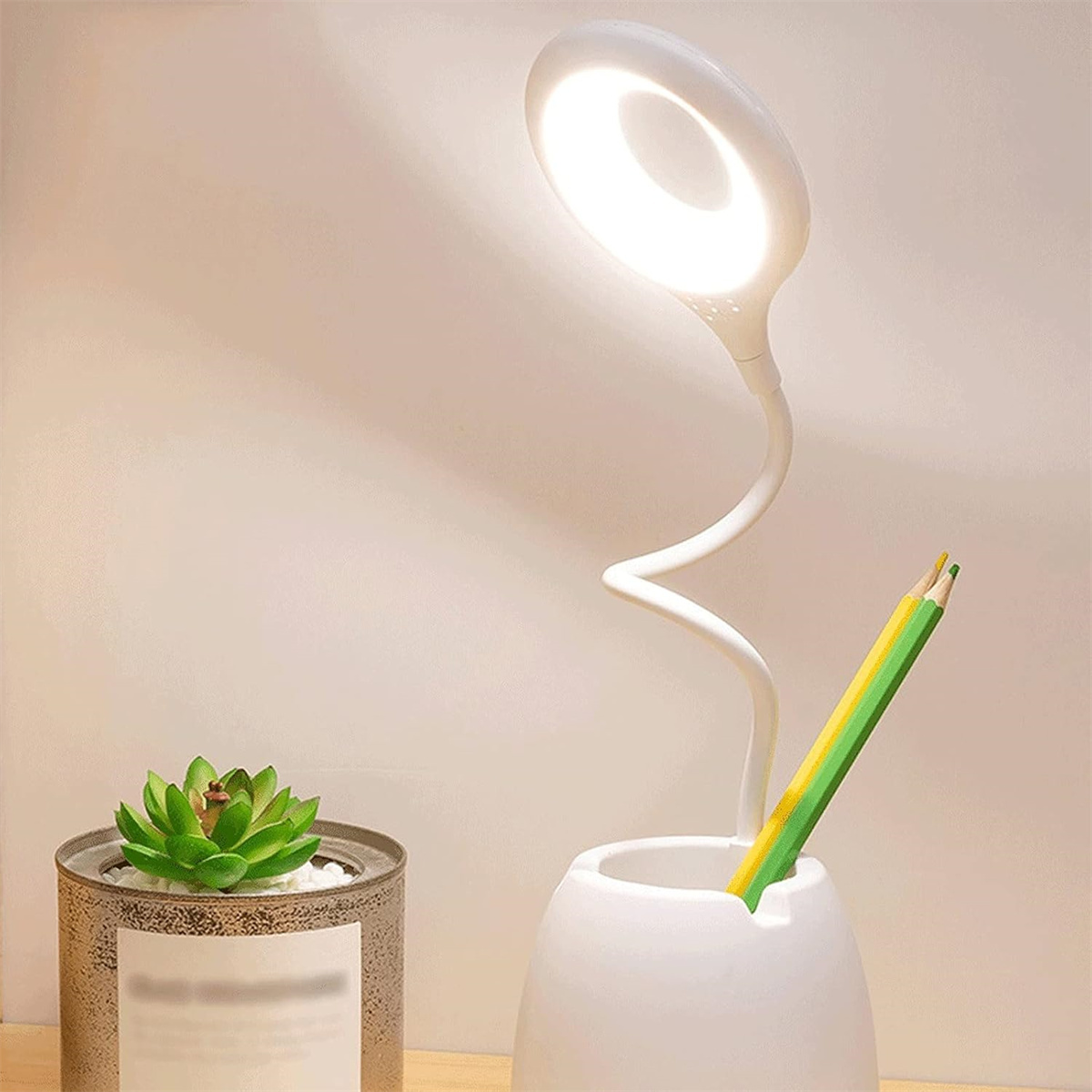 Eine Schreibtischlampe mit flexiblem Hals und einem Stifthalter mit zwei Stiften darin.