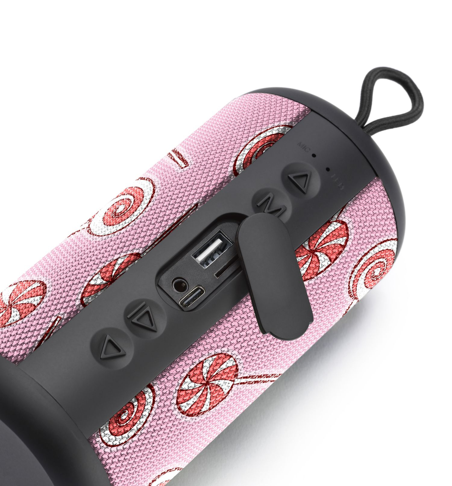 Różowy cylindryczny głośnik z wzorem lizaków, z czarnymi przyciskami i pętlą do zawieszania na białej powierzchni.