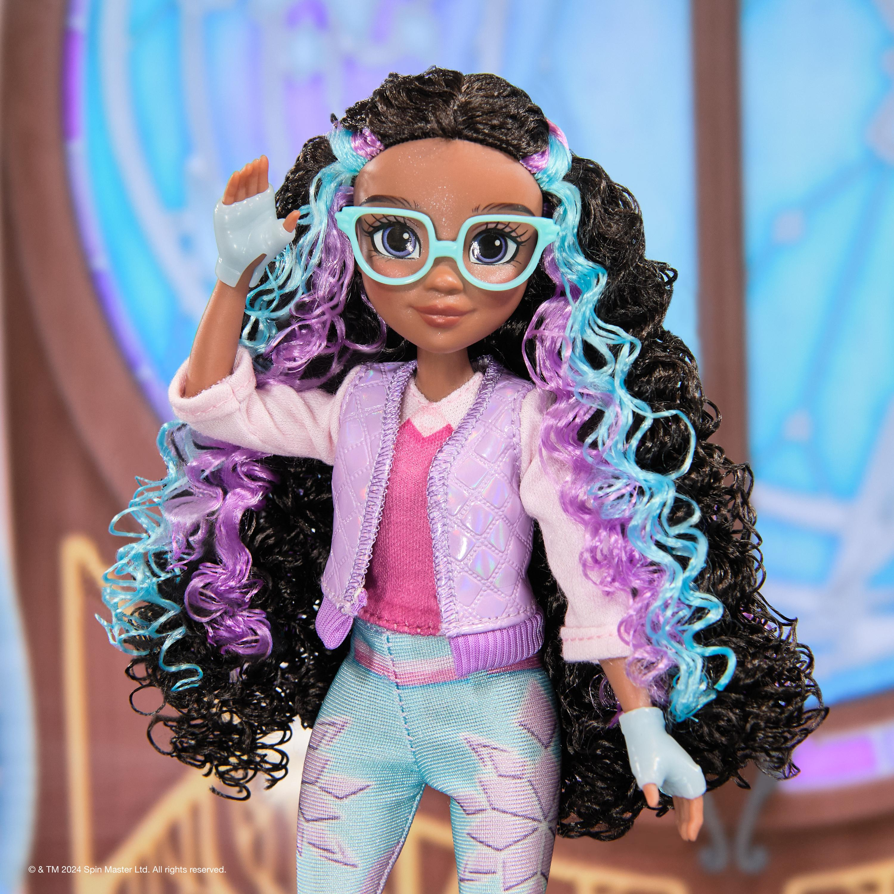 Una muñeca de una niña con gafas y cabello rizado, que lleva una blusa rosa y pantalones azules, con la mano alzada.