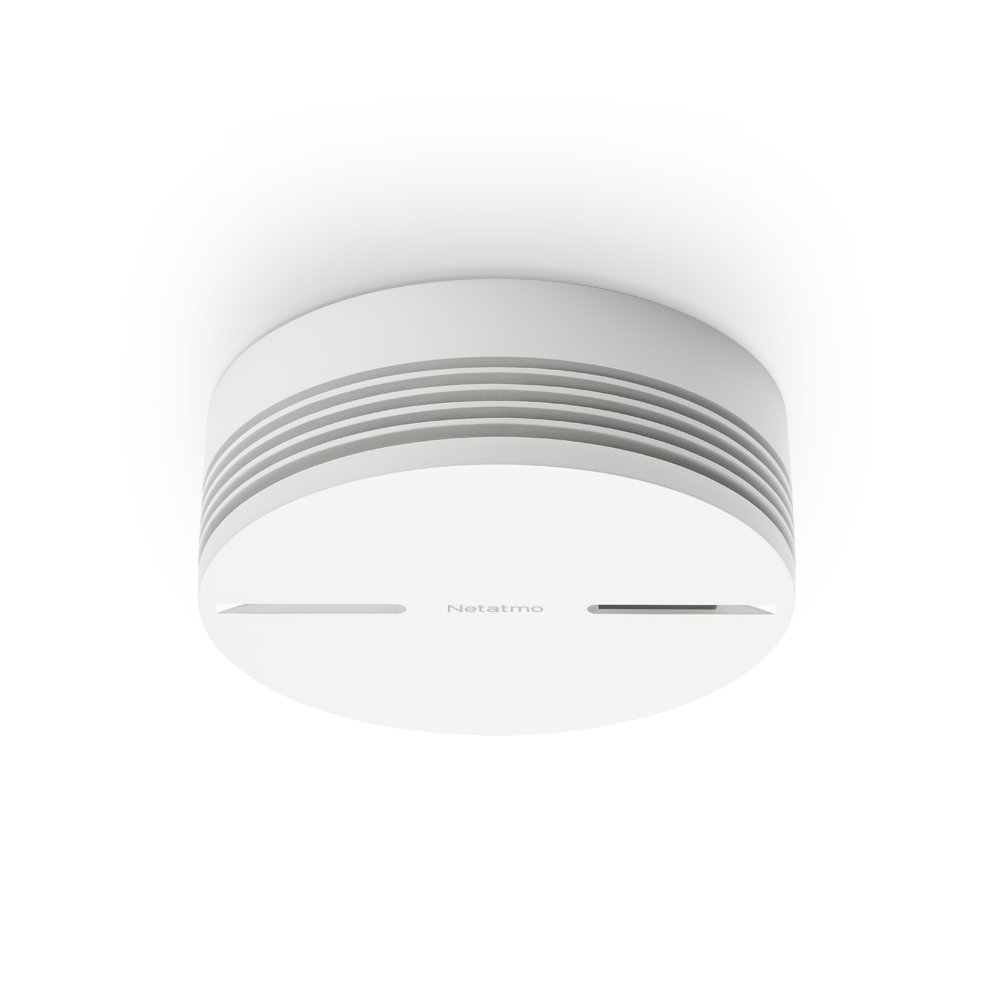 Een witte Netatmo rookmelder, cilindrisch met horizontale ventilatieopeningen. Op een witte achtergrond.