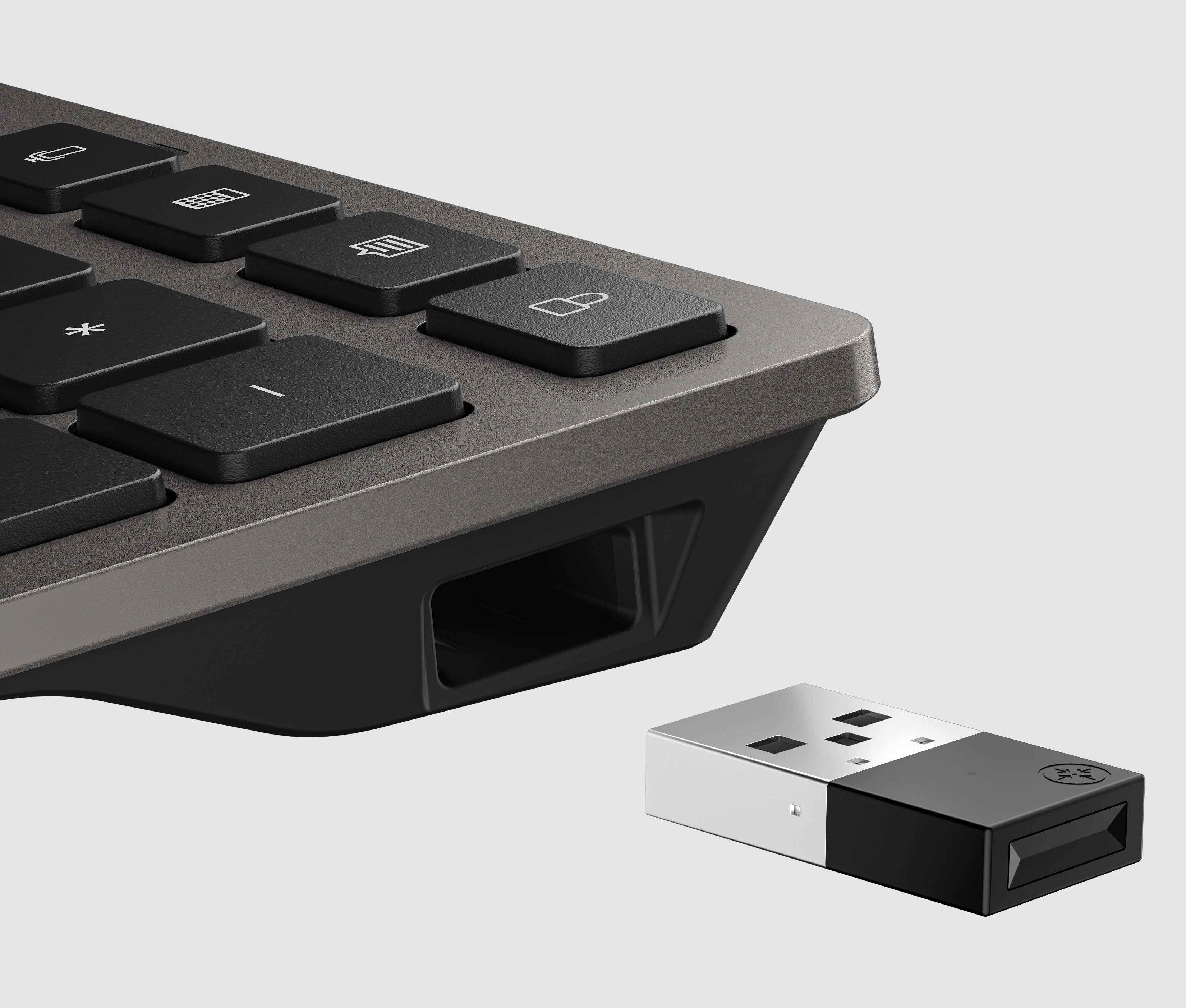 Angolo della tastiera con tasti neri, ricevitore USB accanto.