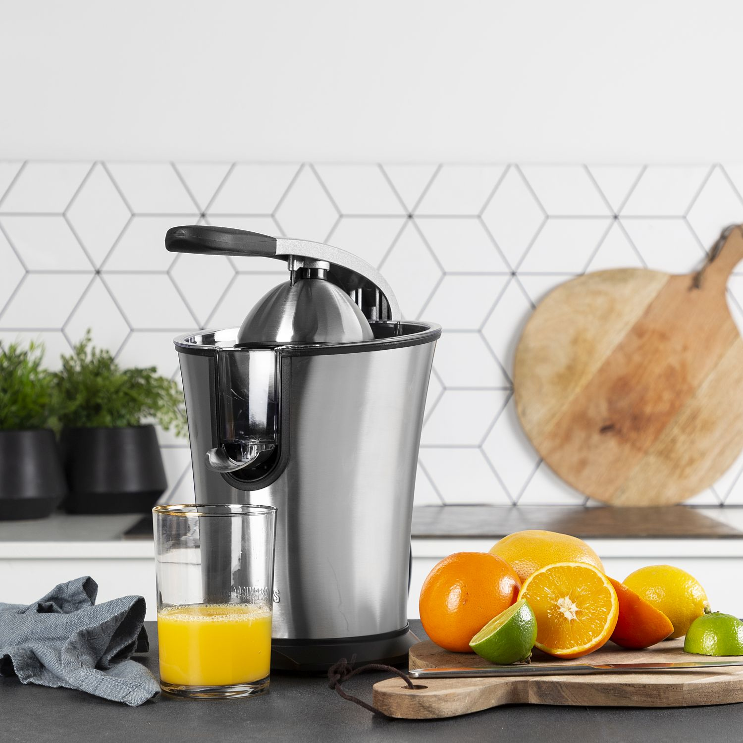 Wyiskarka ze stali nierdzewnej z pomarańczami, limonkami i szklanką soku na czarnym blacie.