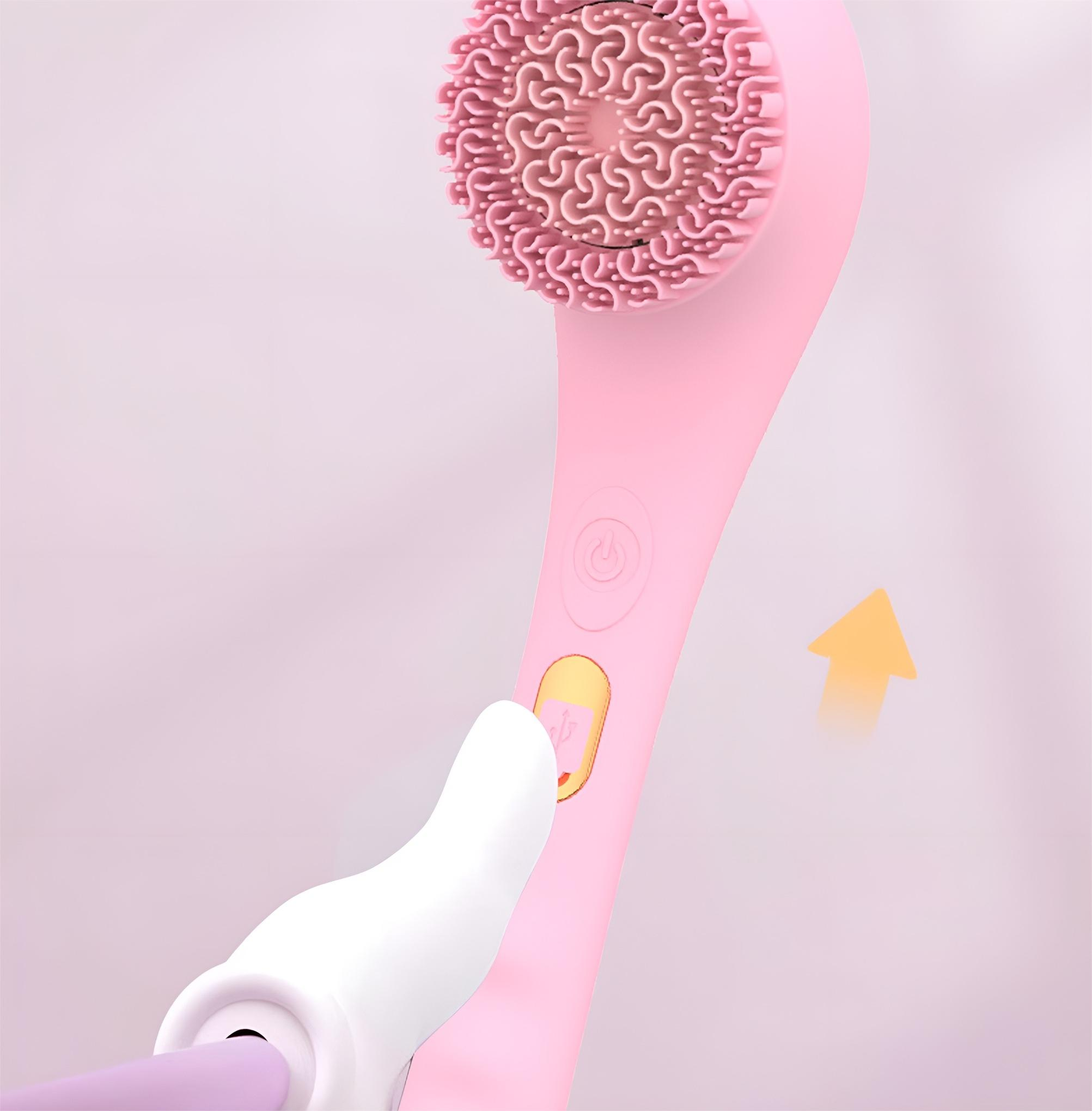 Eine rosa Gesichtsbürste mit einer Hand, die einen Knopf drückt. Ein Pfeil zeigt auf den Ein-/Ausschalter.