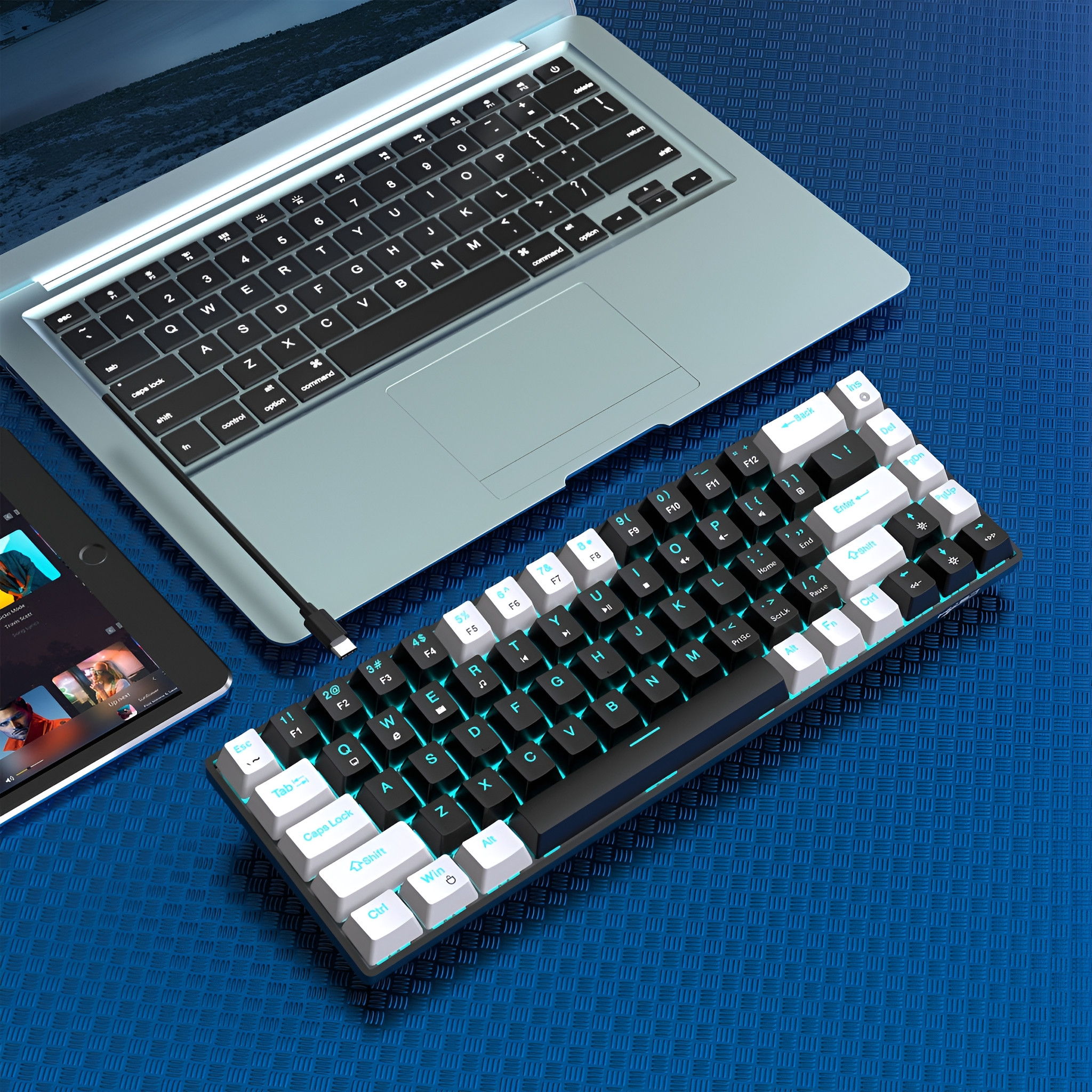 Gaming-Tastatur neben Laptop und Tablet. Tastatur ist schwarz mit weißen Tasten. Blauer Hintergrund.