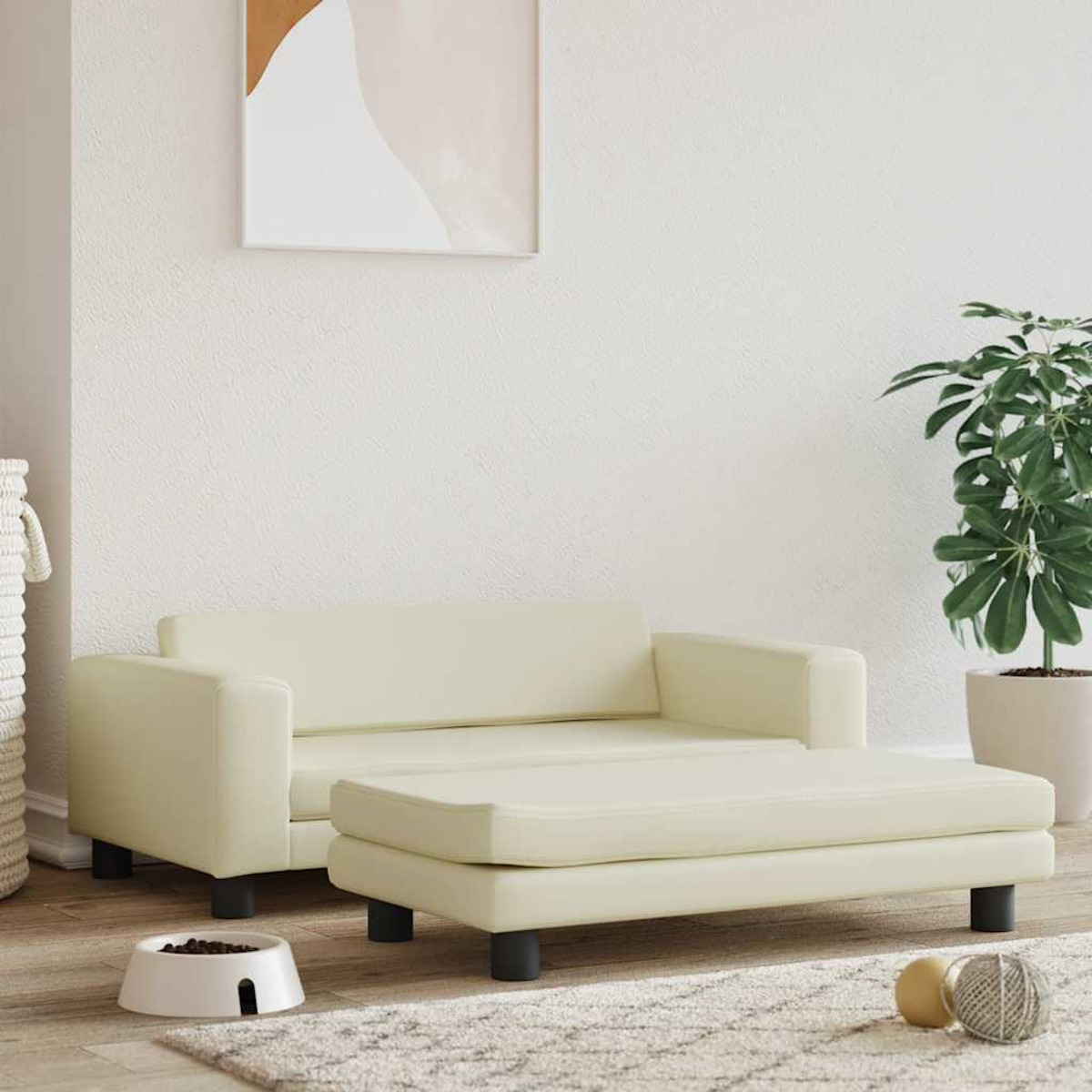 Cremefarbenes Hundesofa und Ottoman auf einem Teppich. Eine Futterschüssel, ein Spielzeug und eine Pflanze sind im Hintergrund.