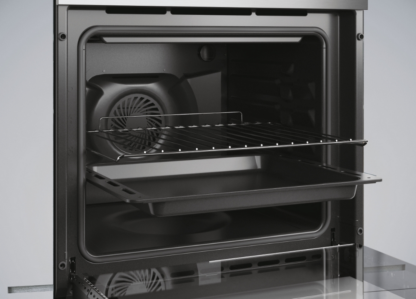 Interno di un forno con griglie e un vassoio. L'interno è scuro, con una ventola sul retro.