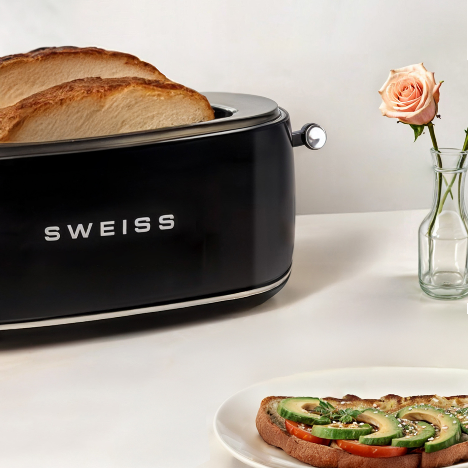 Ein schwarzer Toaster mit Toast und einer Rose in einer Vase auf weißem Grund.