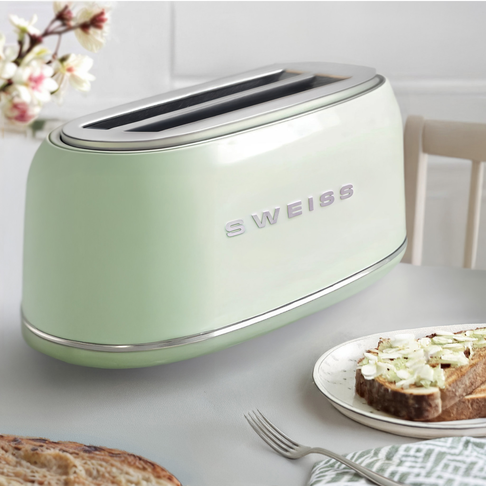 Ein mintgrüner Toaster mit Chromleisten, zwei Schlitzen und dem Wort 'Sweiss'. Toast und Brot stehen auf einem Tisch.