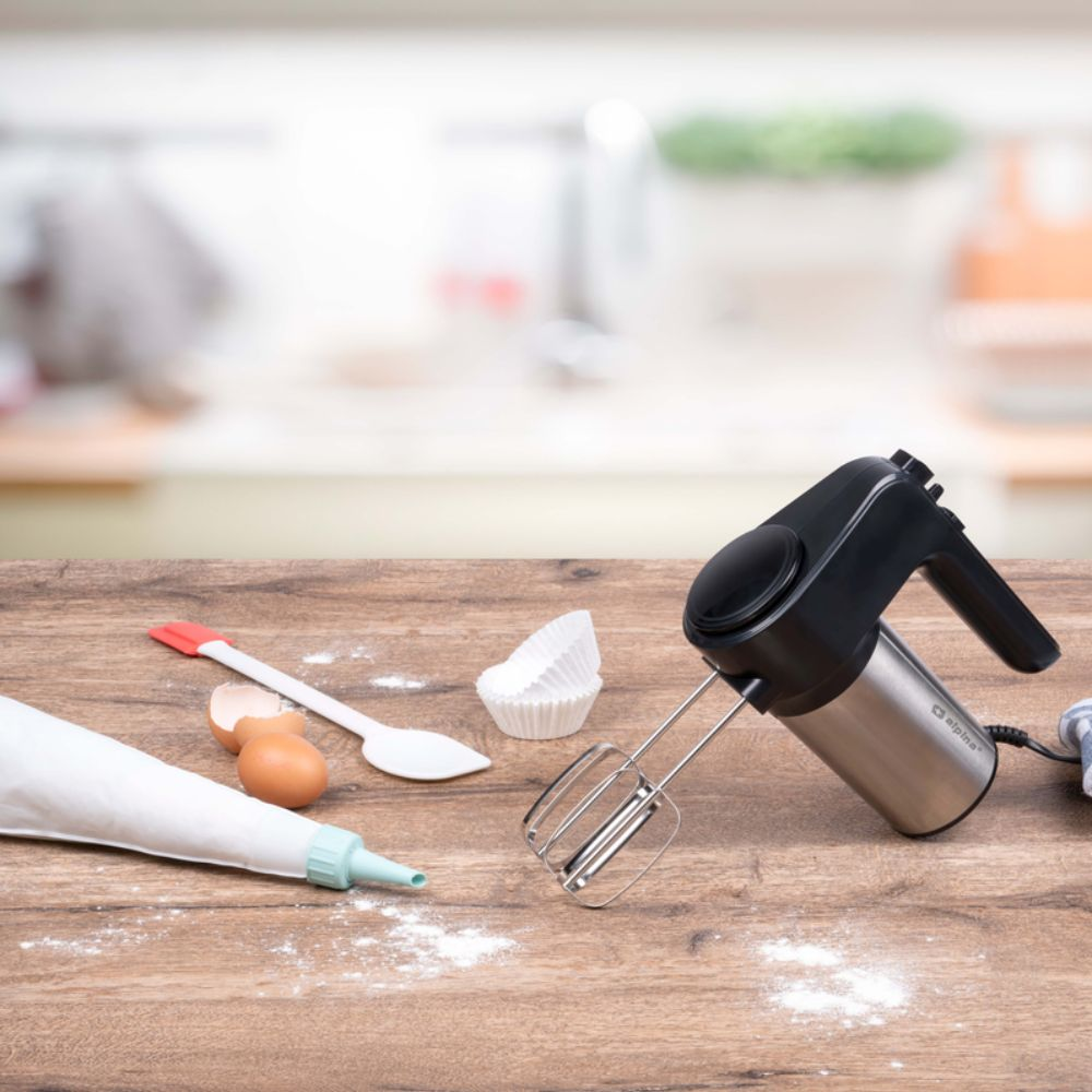 Küchentheke mit Mixer, Eiern, Löffel und anderem Backzubehör.