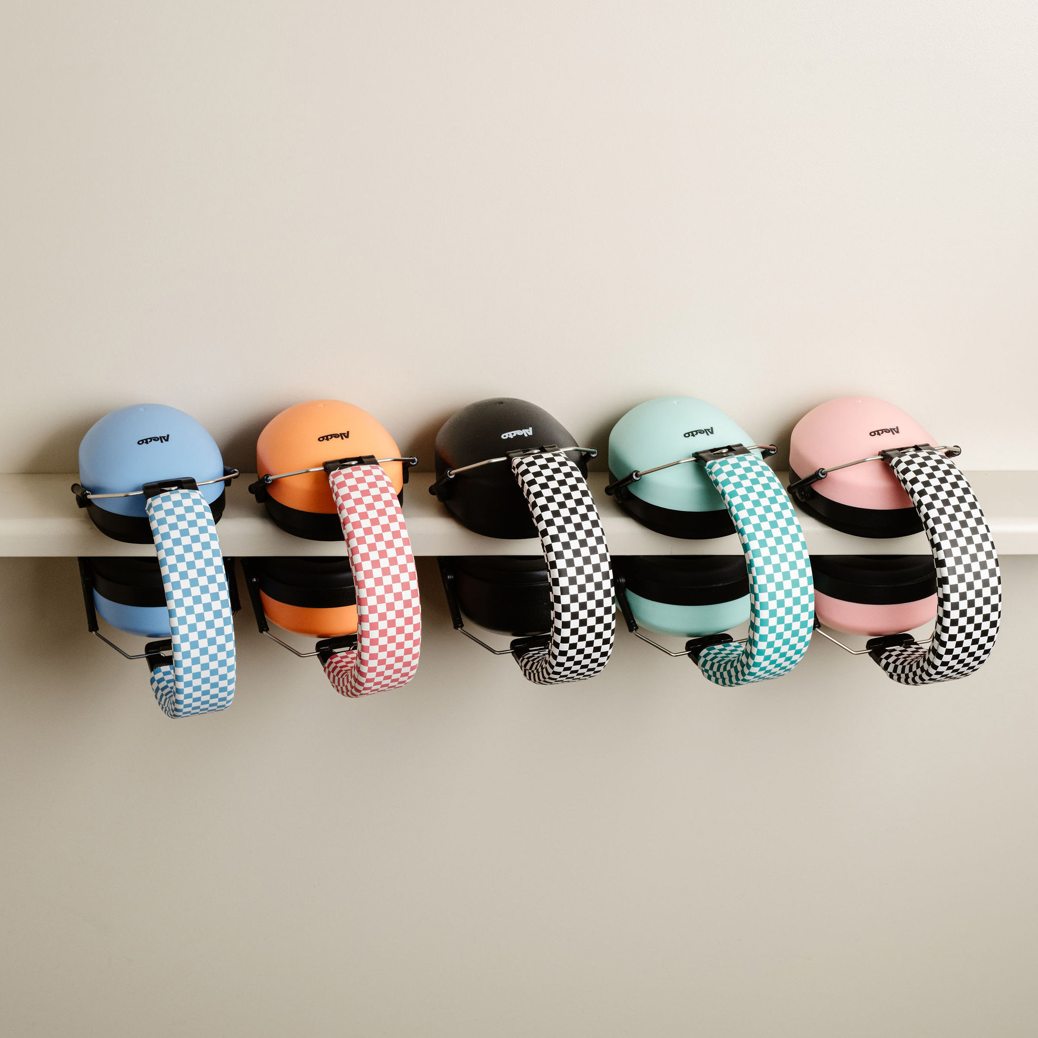 Pięć kolorowych nauszników wiszących na białej ścianie.