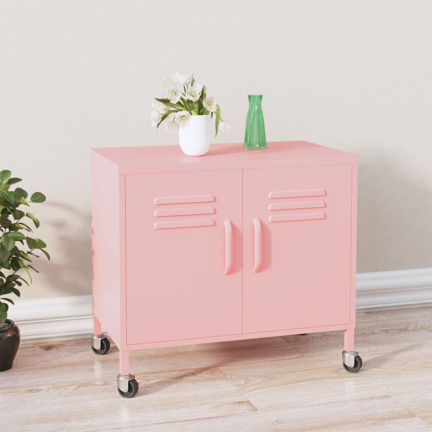 Rosa Schrank mit zwei Türen, Rädern und einer Vase mit Blumen. Links ist eine Pflanze.