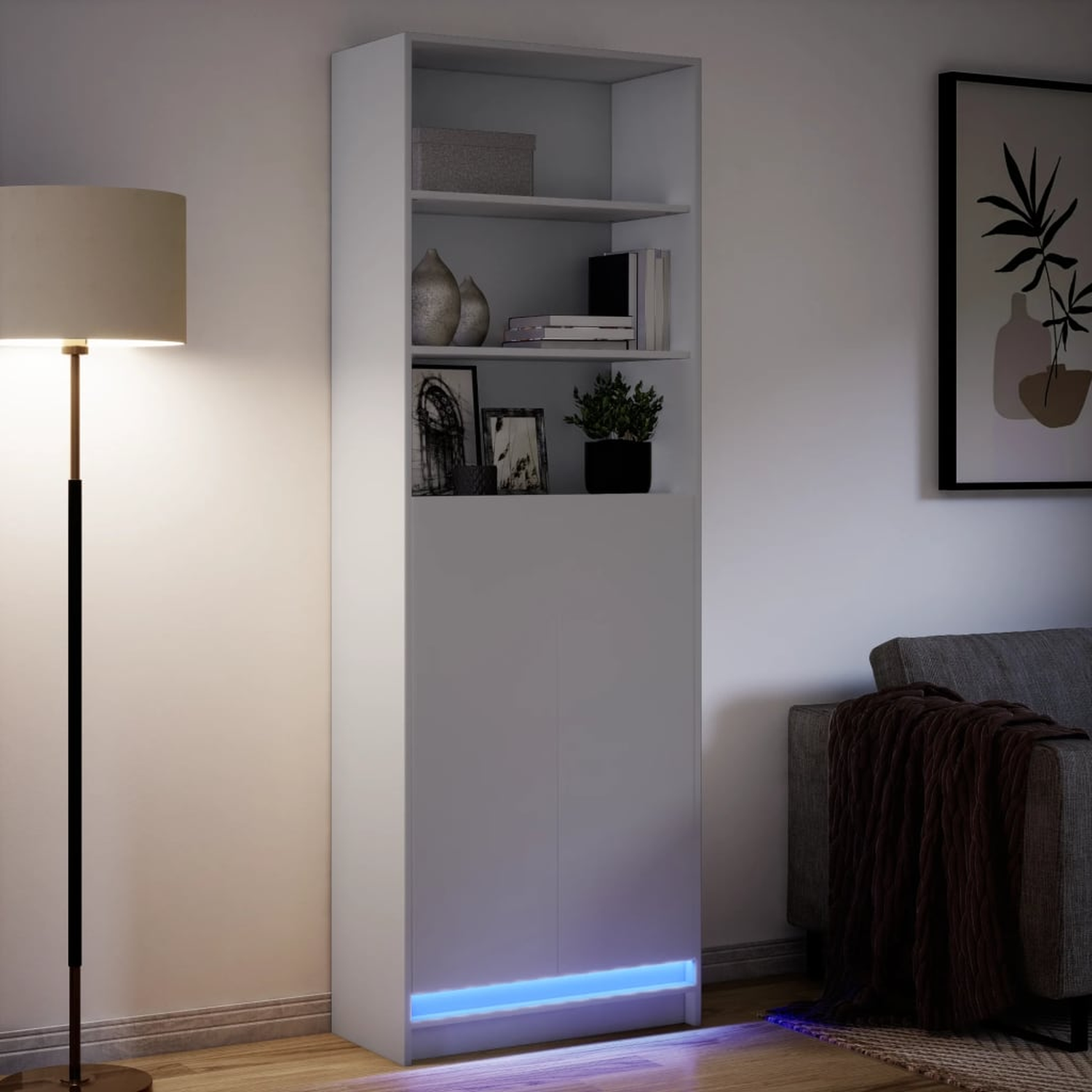 Weißer Schrank mit zwei Türen und Regalen. Bücher, Dekorationen und eine Lampe sind im Bild.