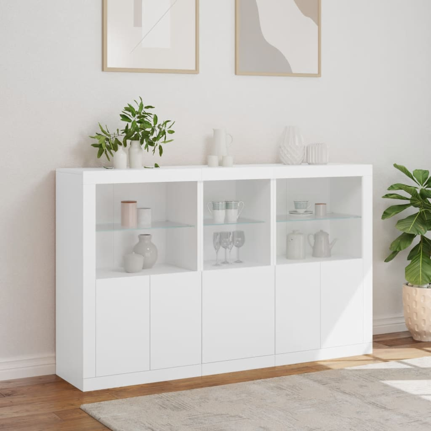Weißer Schrank mit Glastüren, der Gegenstände im Inneren zeigt, vor einer weißen Wand.