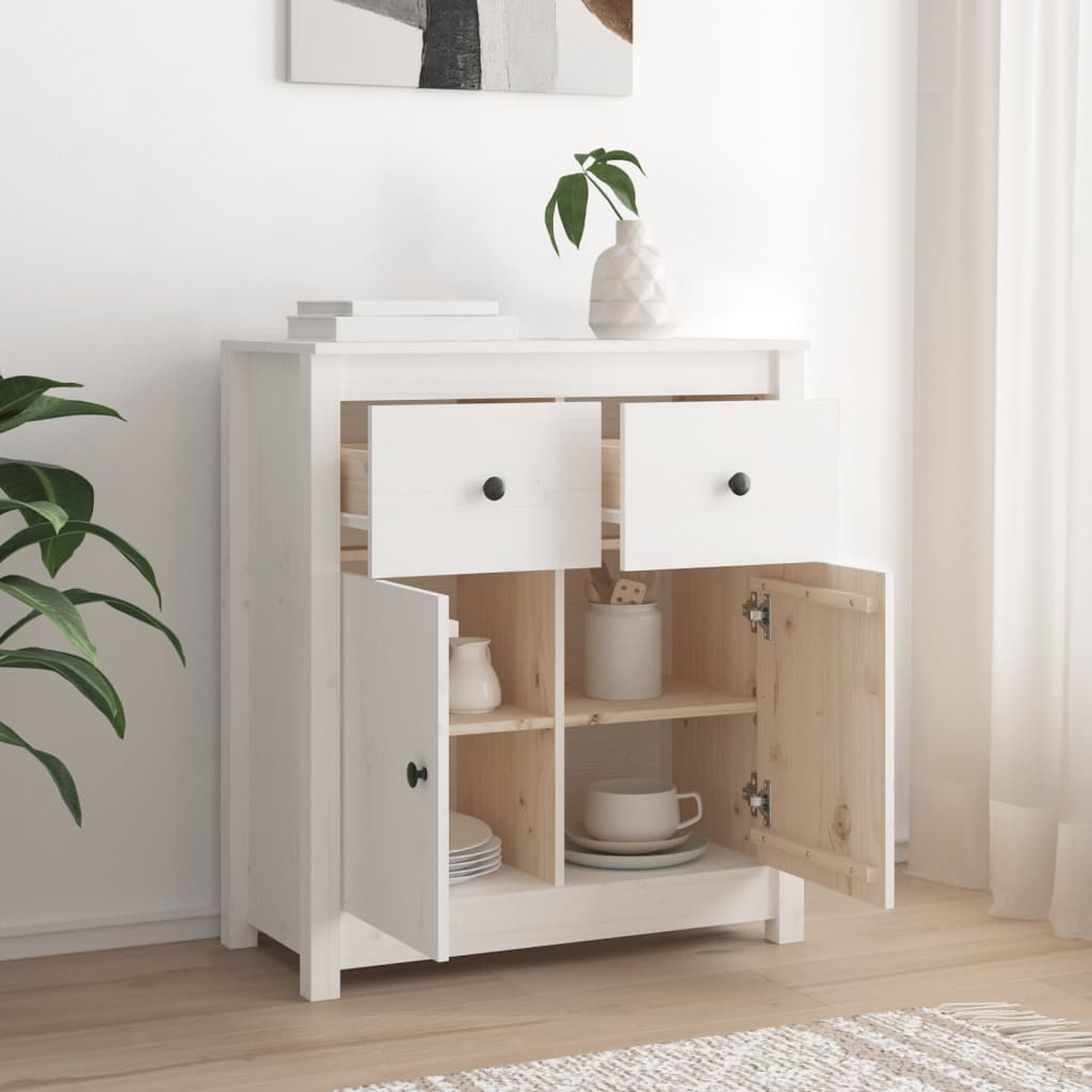 Weißer Schrank mit zwei Schubladen und offenen Türen. Einige Gegenstände innen. Weiße Wand und Pflanze.
