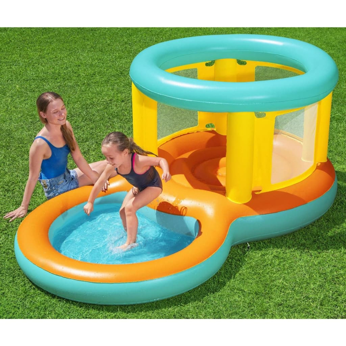 Dos chicas en traje de baño jugando en una piscina inflable colorida sobre césped verde.