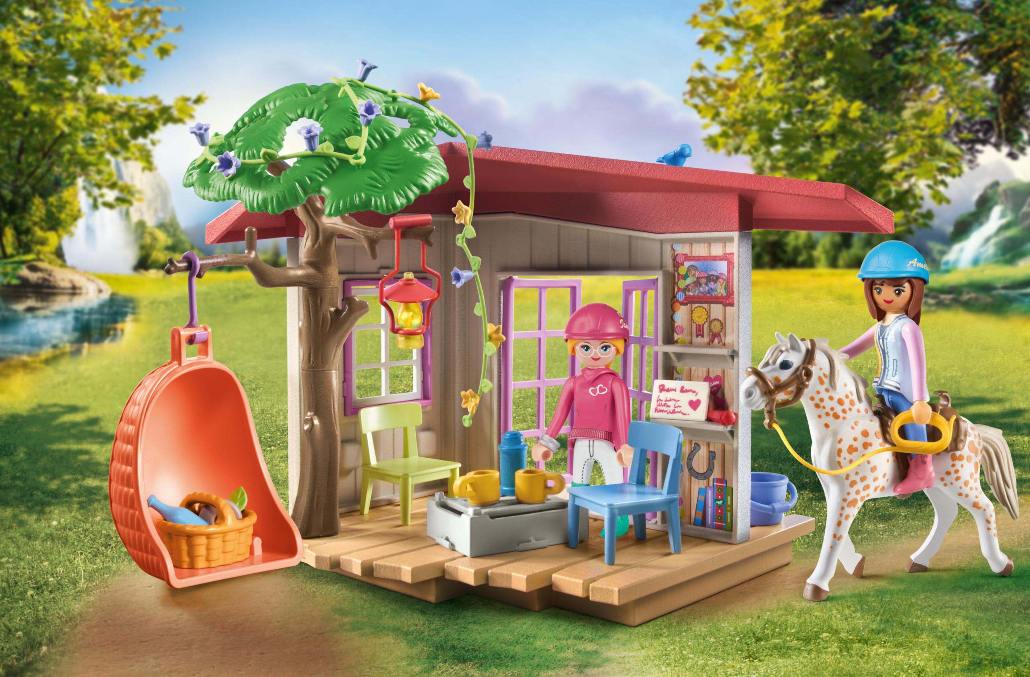 Scena della stalla dei cavalli Playmobil con due figure, un cavallo e vari accessori, in un giardino.