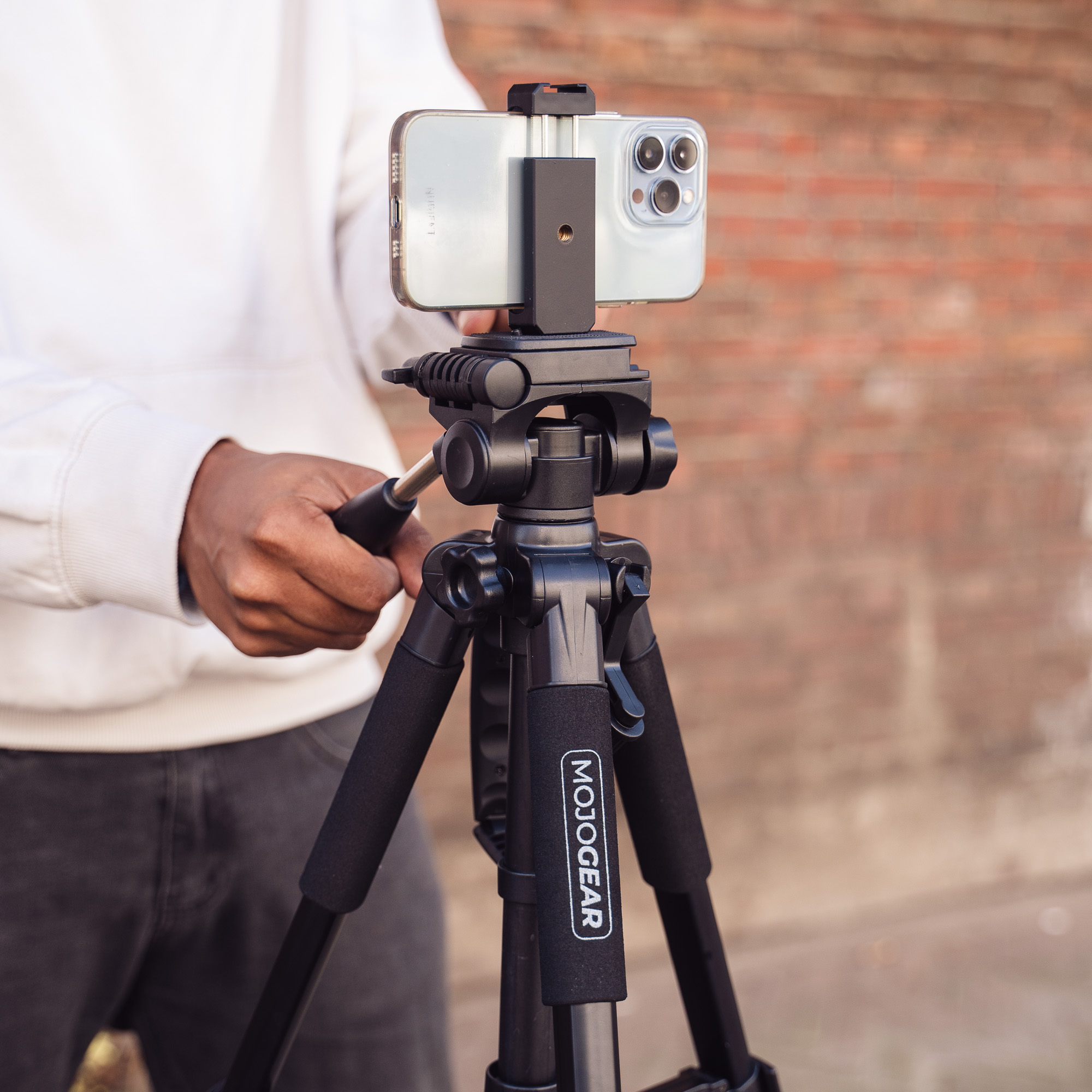 A person adjusts a phone on a tripod. The tripod has a phone mount.