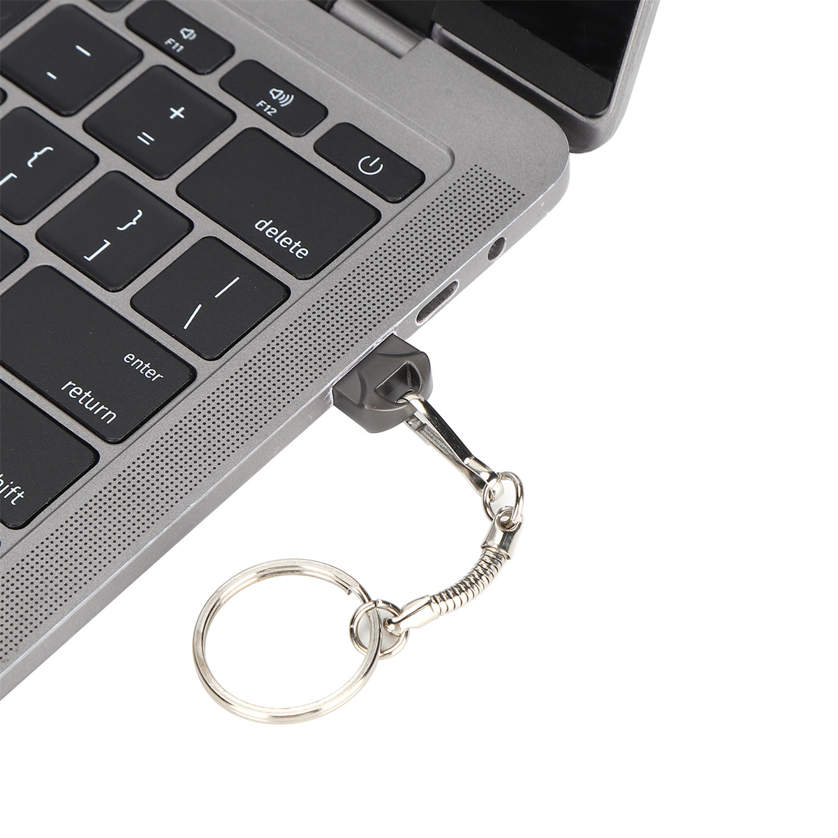 Ein grauer USB-Stick, der an einem Schlüsselanhänger und Laptop befestigt ist.