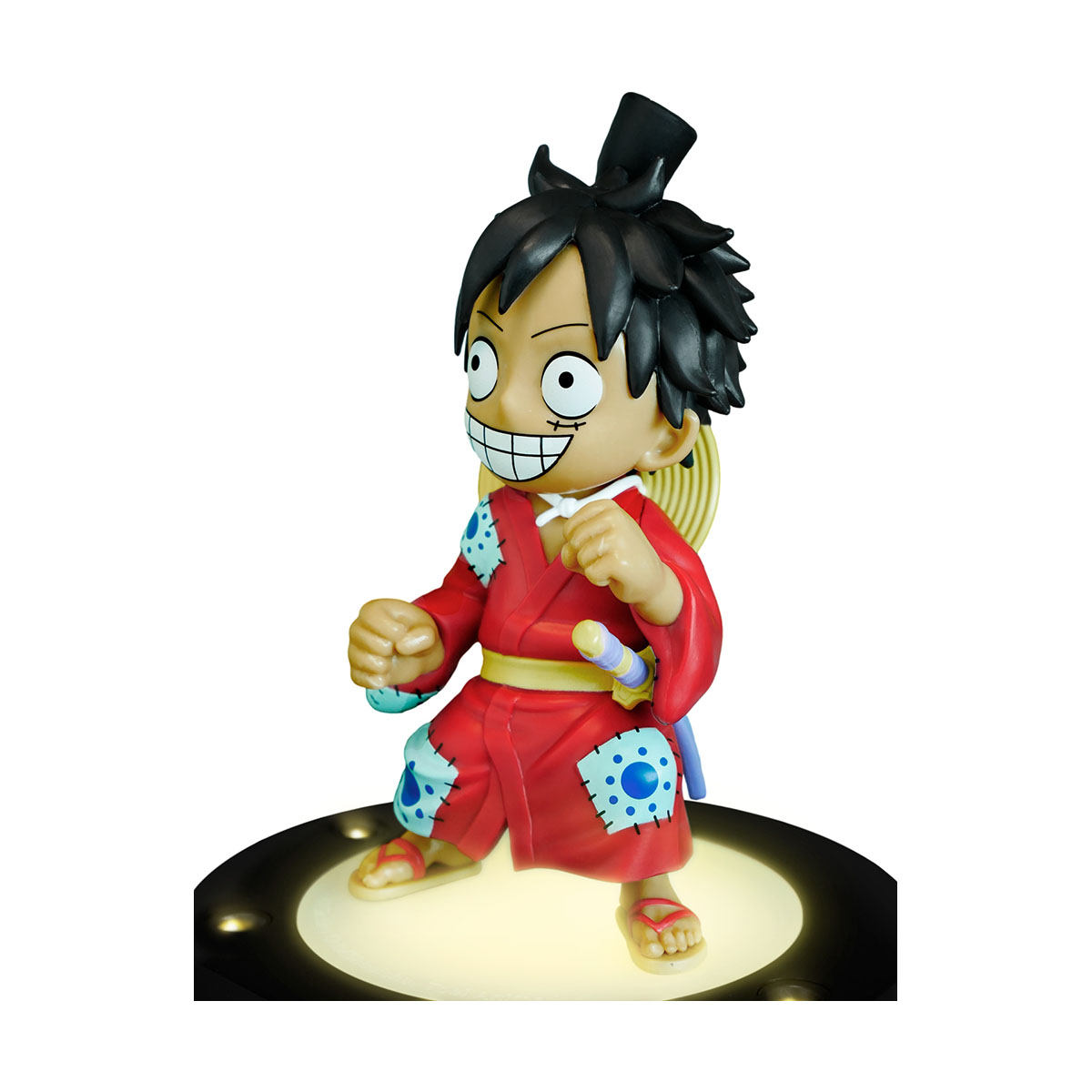 Figur einer Zeichentrickfigur in einem roten Kimono, mit lächelndem Gesicht, auf einem Licht stehend.