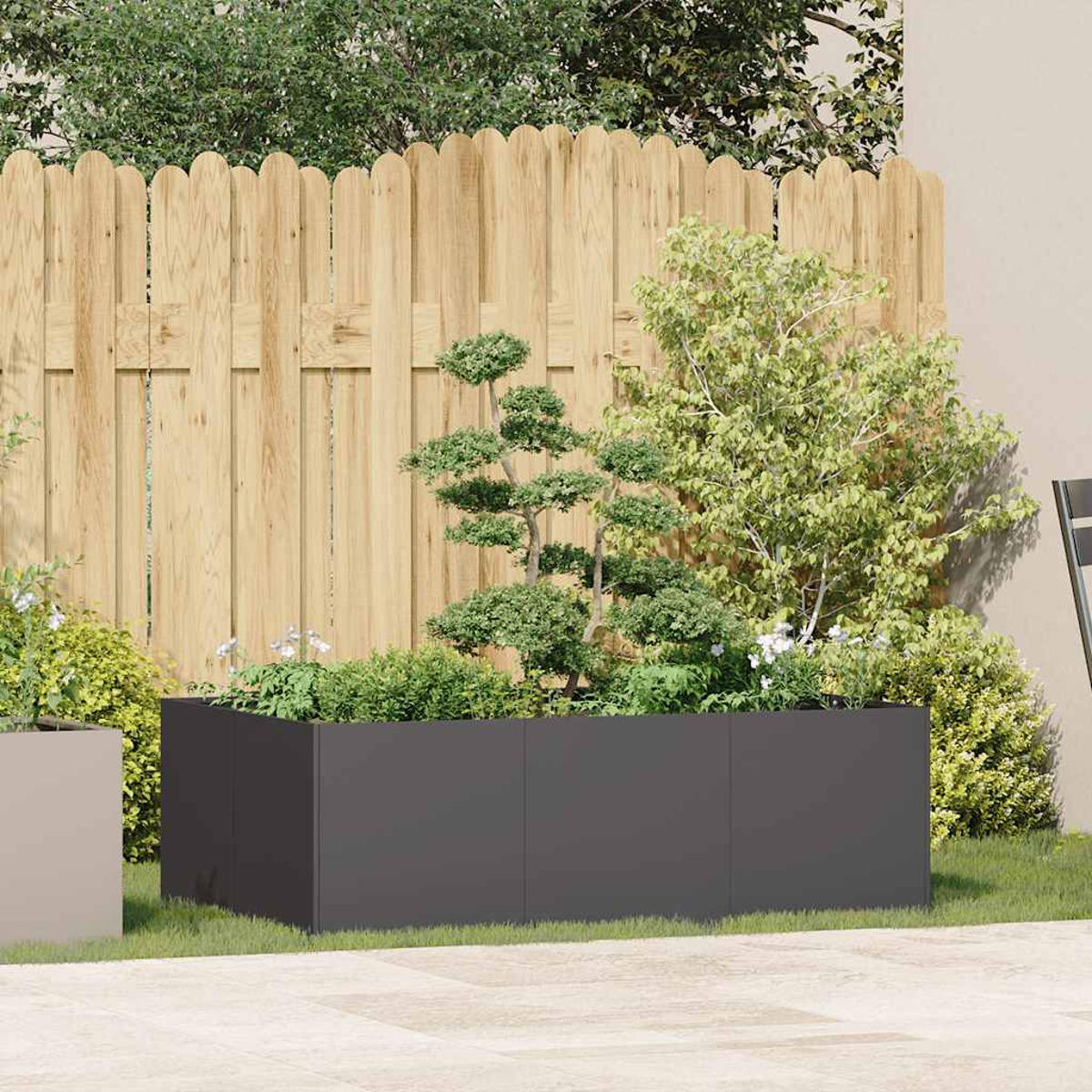 Fioriera in un giardino. Fioriera grigio scuro piena di piante, contro una recinzione in legno e alberi.