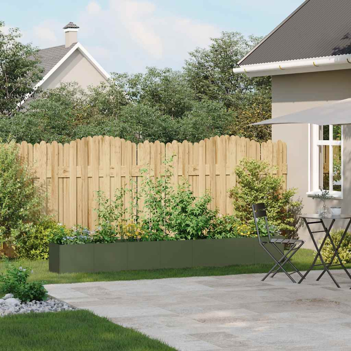 Giardino con recinzione in legno, aiuola rialzata, piante, patio e casa sullo sfondo.