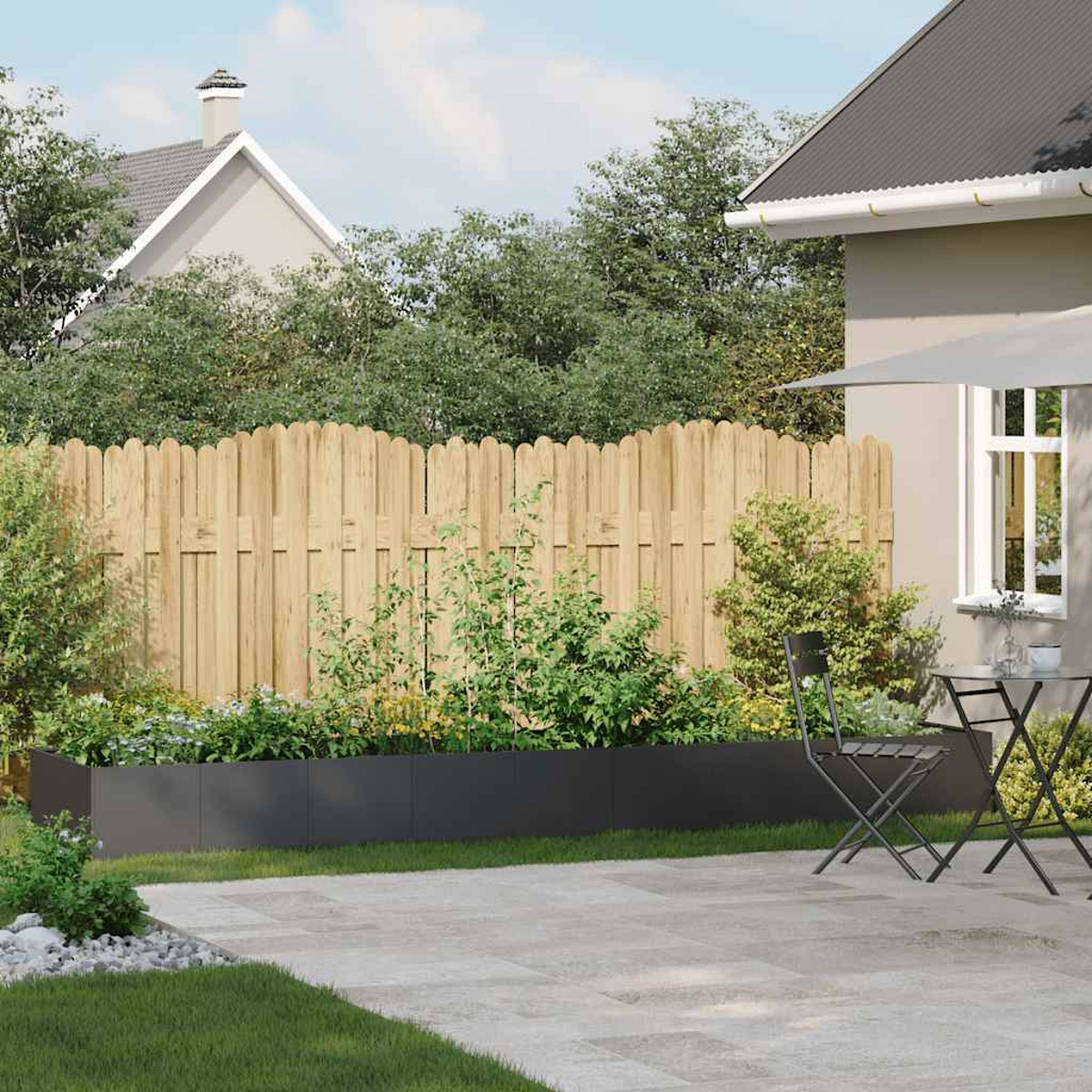 Giardino con recinzione in legno, aiuola rialzata, piante, patio e casa sullo sfondo.