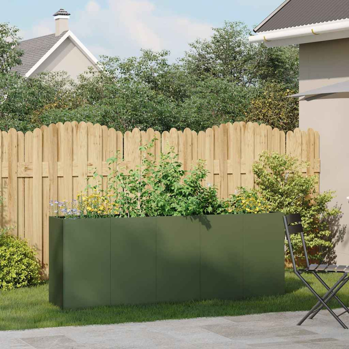 Grüner Pflanzkübel mit Pflanzen in einem Garten. Zaun und Stuhl im Hintergrund.