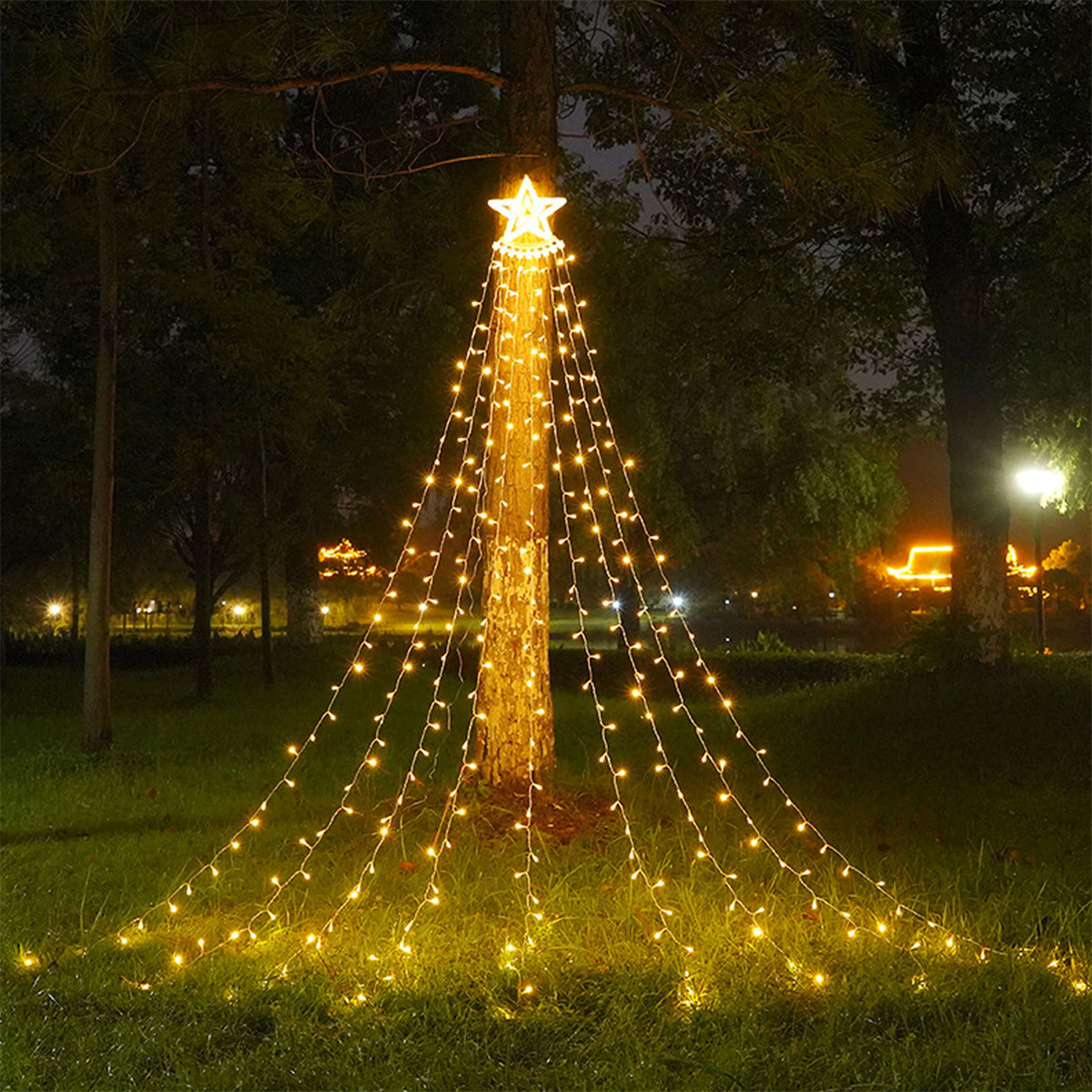 Ein Baum mit Stern oben, dekoriert mit herabfallenden Lichtern, in einer Nachtszene.