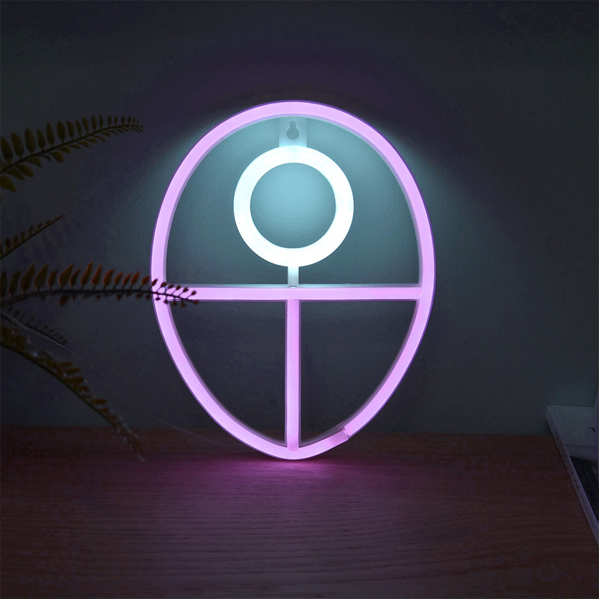 Ein Neonzeichen in Form eines Kreises mit horizontaler und vertikaler Linie, rosa und weiß leuchtend.