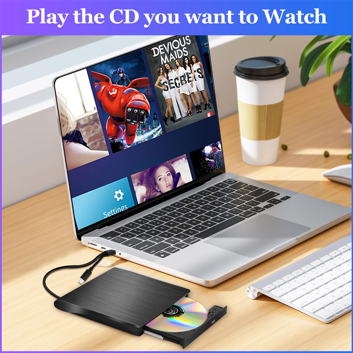 Ein Laptop zeigt eine Filmszene. Ein CD-Player befindet sich auf dem Schreibtisch neben einer Tastatur und einer Kaffeetasse.