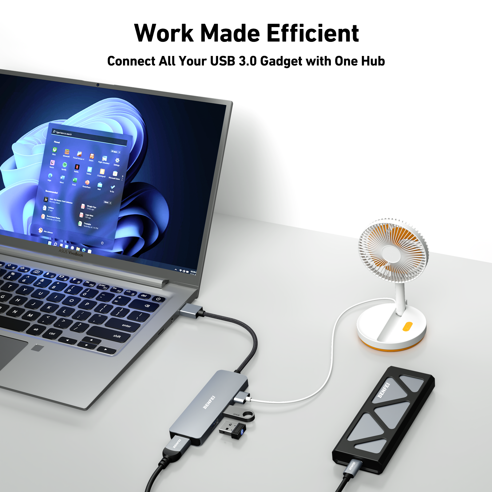 Ein Laptop, verbunden mit einem Hub und anderen Geräten, einem Ventilator und einer Festplatte, auf weißer Oberfläche.