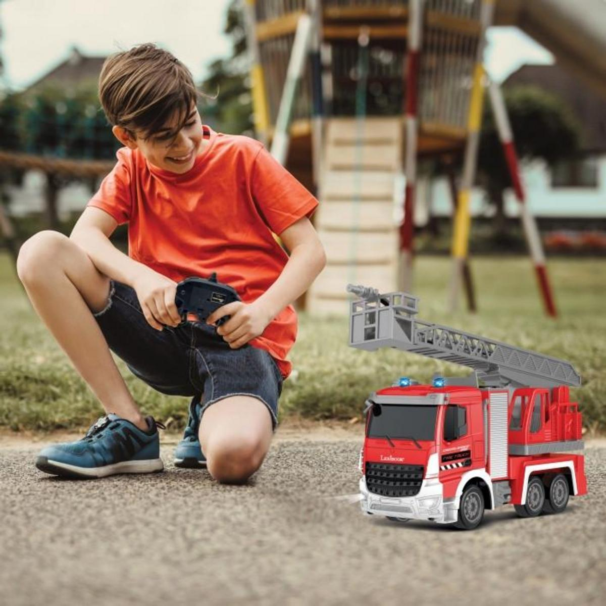 Un niño juega con un camión de bomberos de juguete rojo. El fondo muestra un parque infantil.