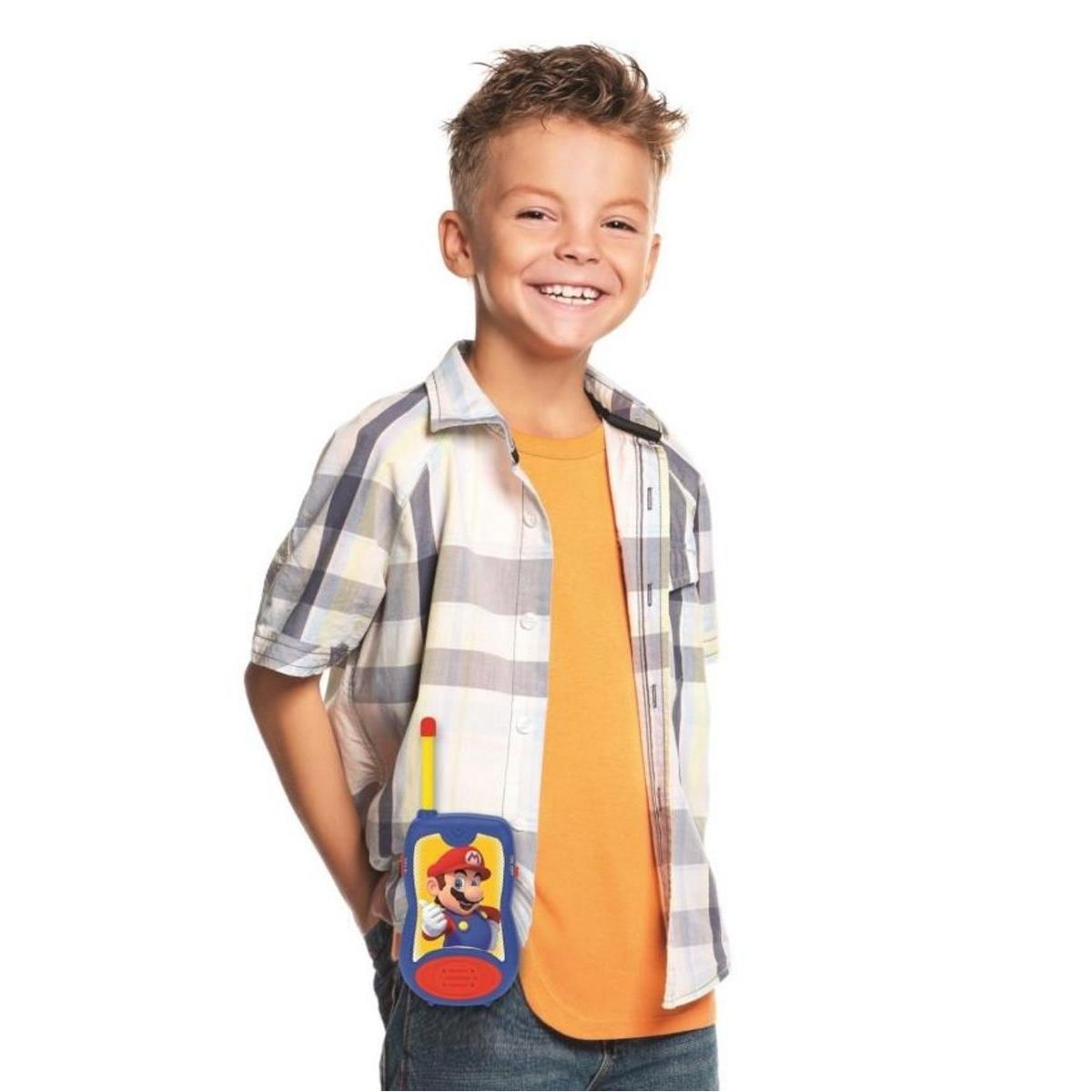 Niño con camisa naranja y camisa a cuadros, sosteniendo un walkie-talkie de Mario en el bolsillo.