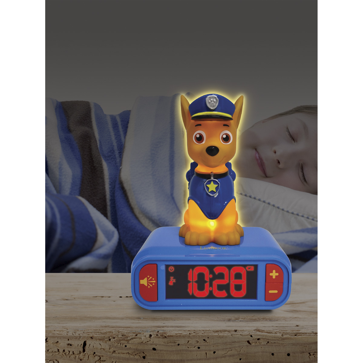 Ein Paw Patrol Chase Nachtlicht auf einer blauen Uhr. Im Hintergrund schläft ein Kind. Die Uhrzeit ist 10:28.