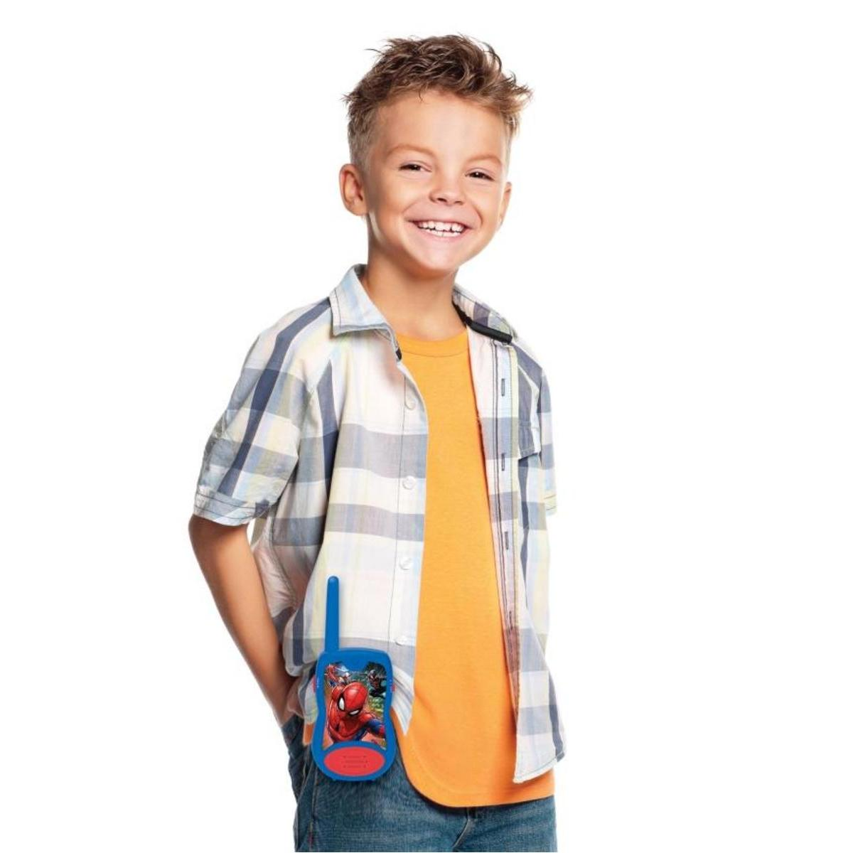 Niño con camisa naranja y camisa a cuadros, sosteniendo un walkie-talkie de Spider-Man en el bolsillo.
