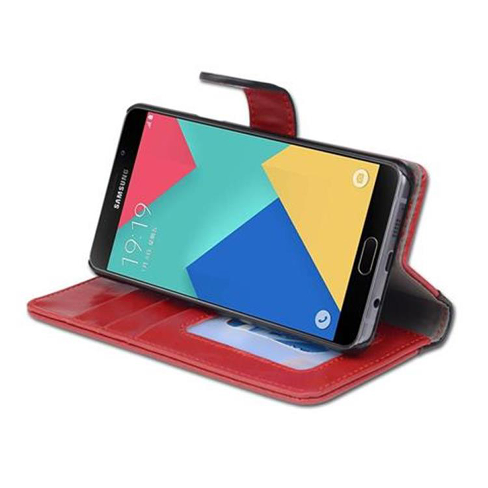Un teléfono en una funda roja está en un soporte rojo, mostrando una pantalla de aplicación colorida.