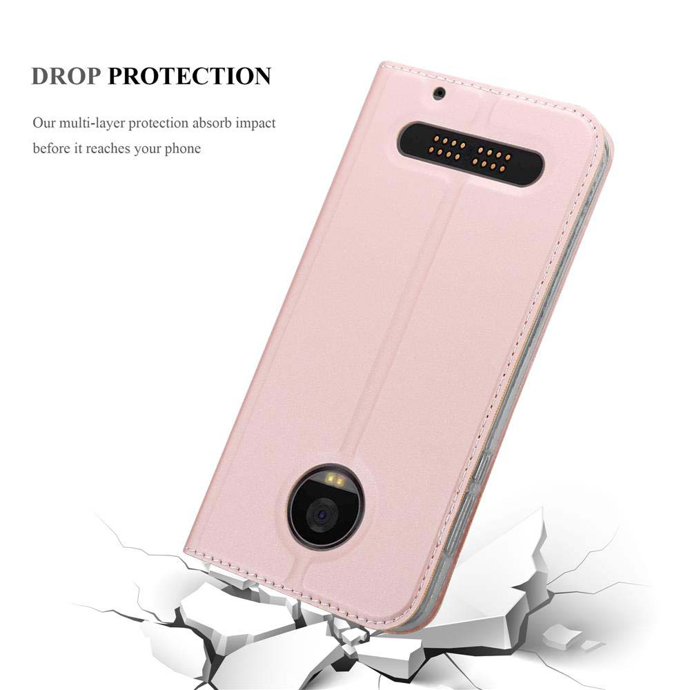 Funda rosa con agujero para cámara y texto 'Drop Protection'. La funda está sobre una superficie rota.