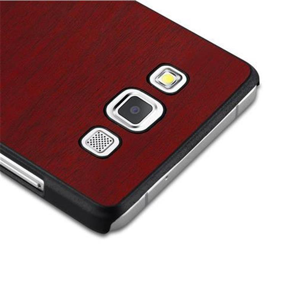 Primer plano de la parte trasera de un teléfono con cámara, flash y altavoz sobre textura de veta de madera.