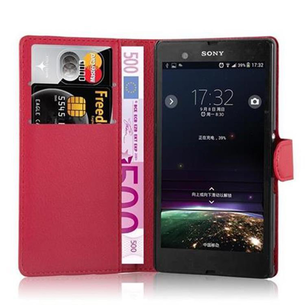 Eine rote Handyhülle im Brieftaschenstil ist geöffnet, mit Karten und Geld darin. Ein Telefon zeigt den Startbildschirm.