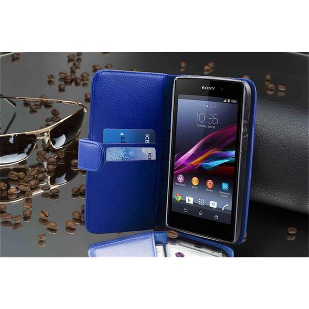 Un teléfono en una funda azul, abierto. Un par de gafas de sol y algunos granos de café están sobre la mesa.