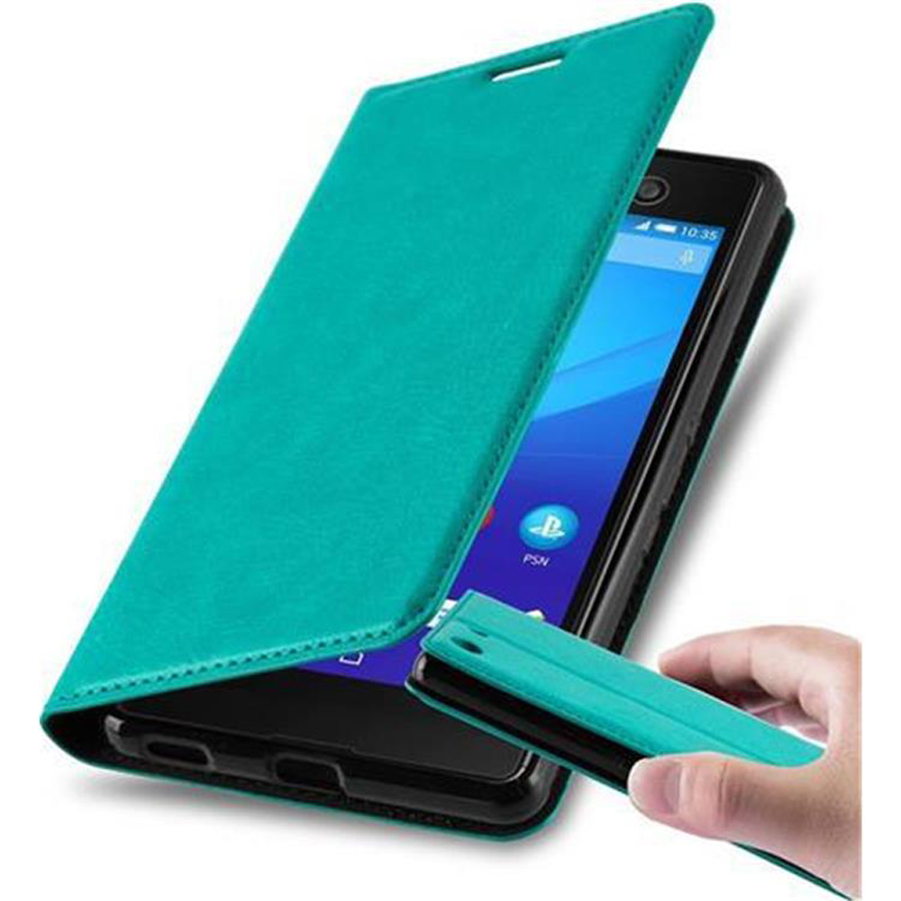 Funda de teléfono verde azulado con tapa abierta y teléfono dentro. Mano sosteniendo una pequeña tapa verde azulado.