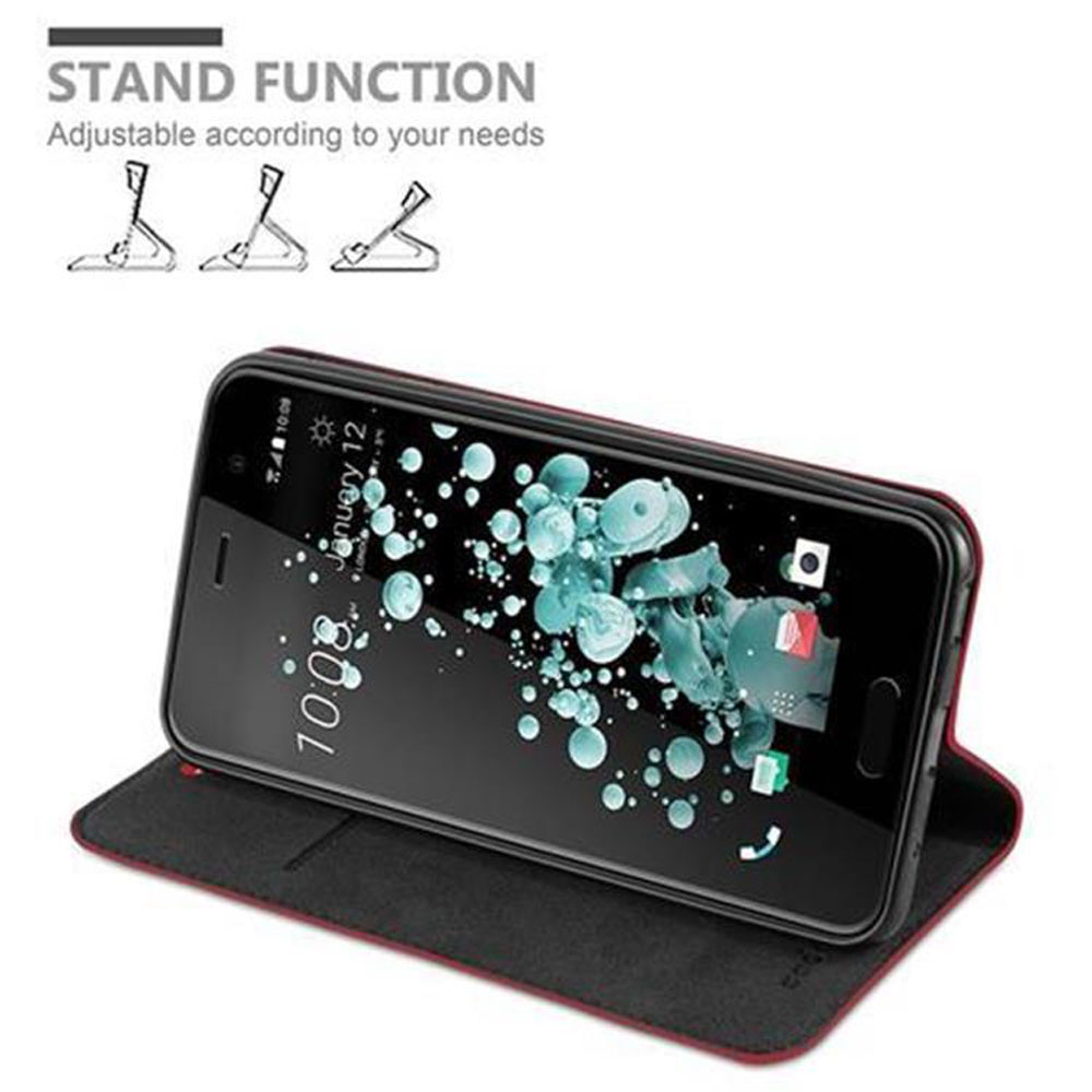Ein Telefon in einer schwarzen Hülle. Der Bildschirm des Telefons zeigt Informationen. Text oben: 'Standfunktion'.