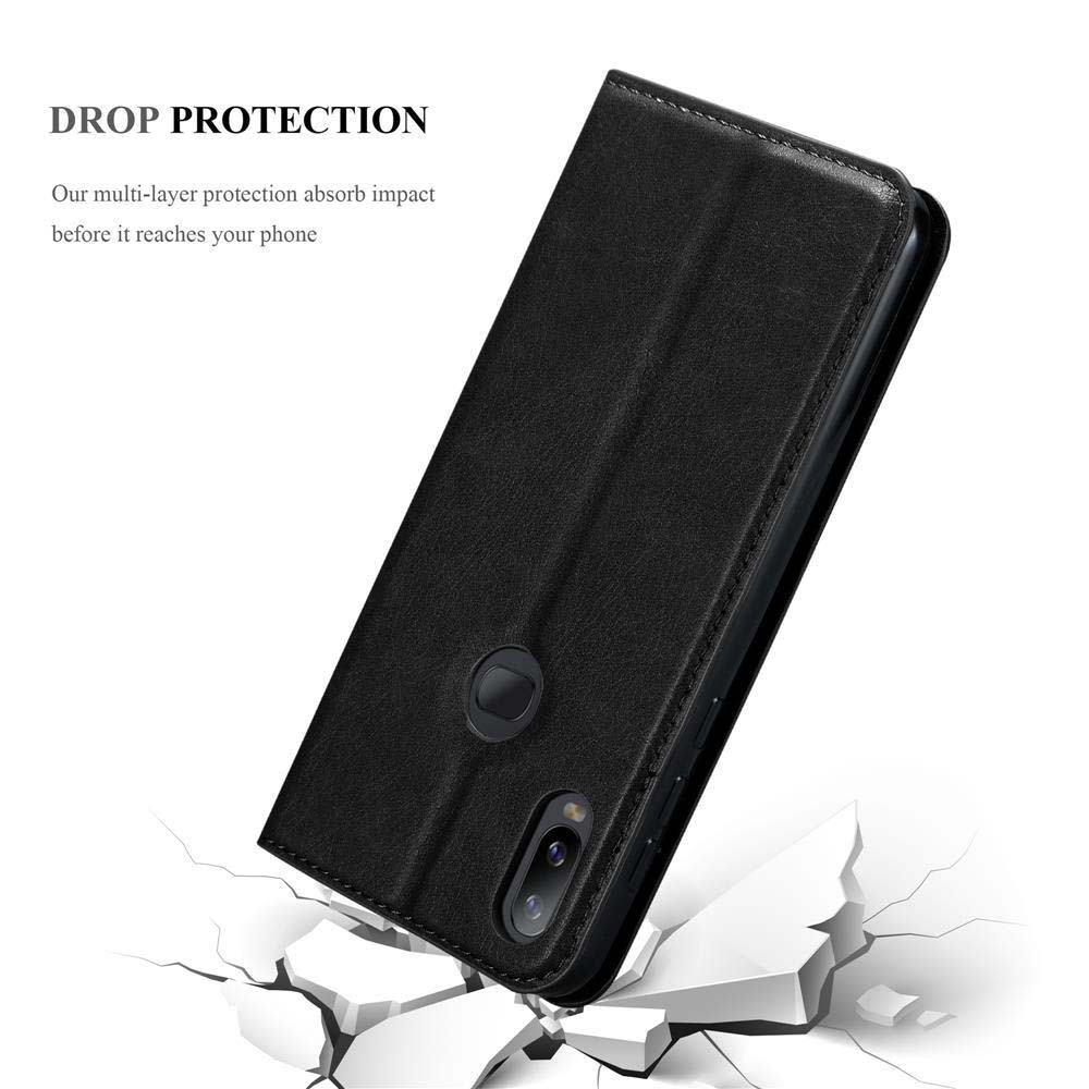 Telefono nero in una custodia di pelle nera. Sono visibili crepe sul terreno.