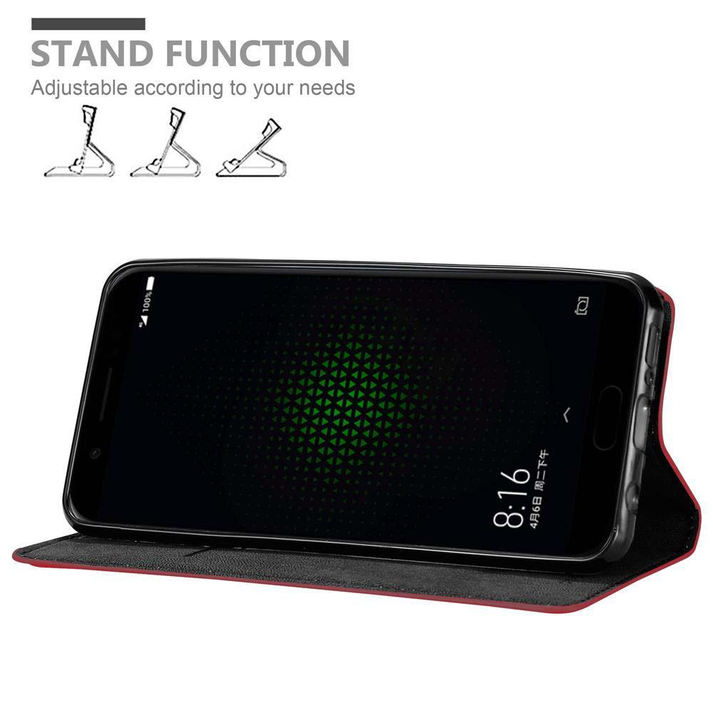 Ein schwarzes Telefon in einem roten Case, aufgestellt. Der Bildschirm zeigt grünes Design. Standfunktion.